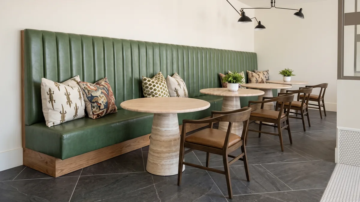Clubhouse banquette with stone pedestal tables and wood chairs