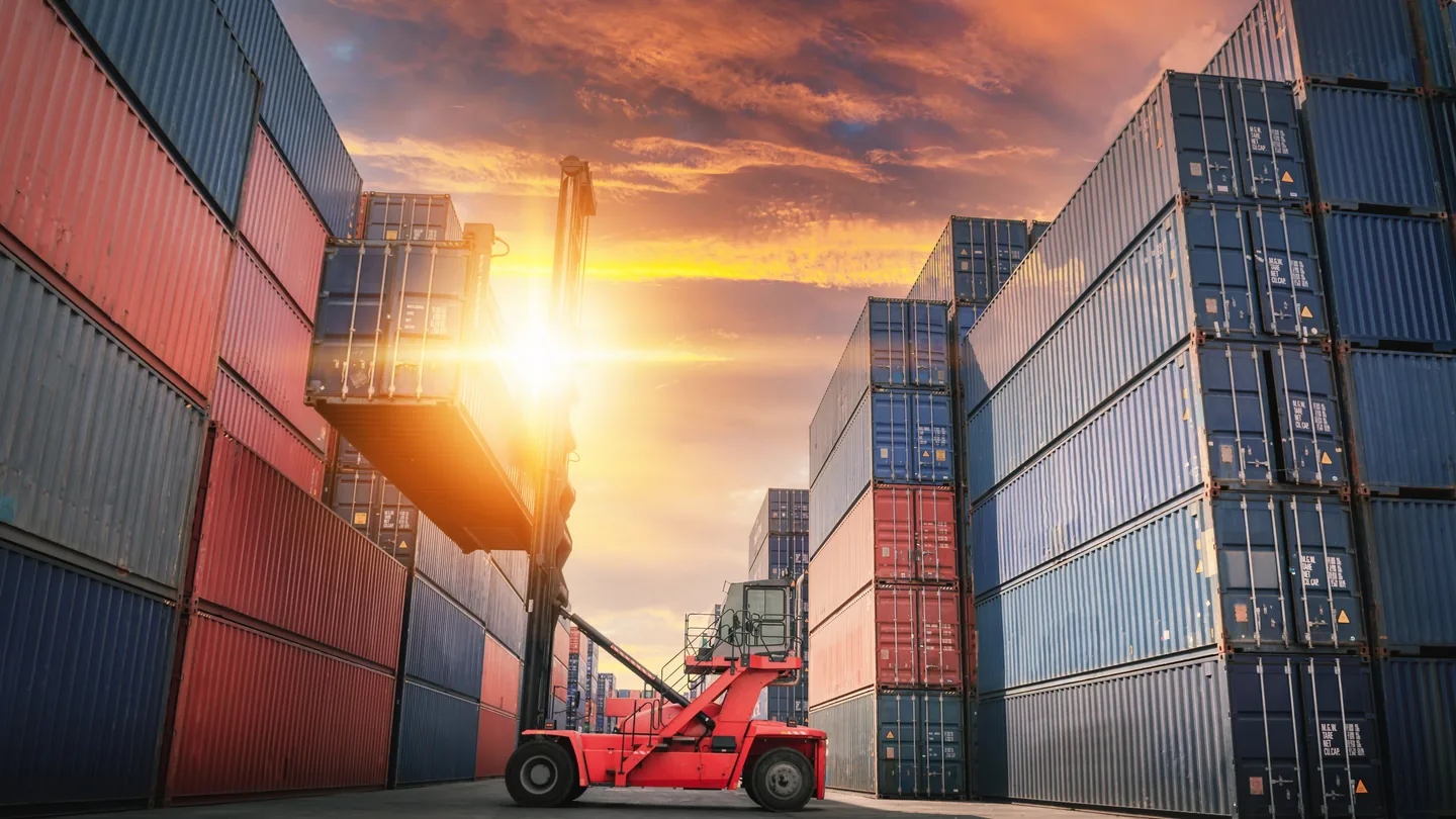 Container yard at a shipping terminal with a reach stacker moving a container for ocean freight