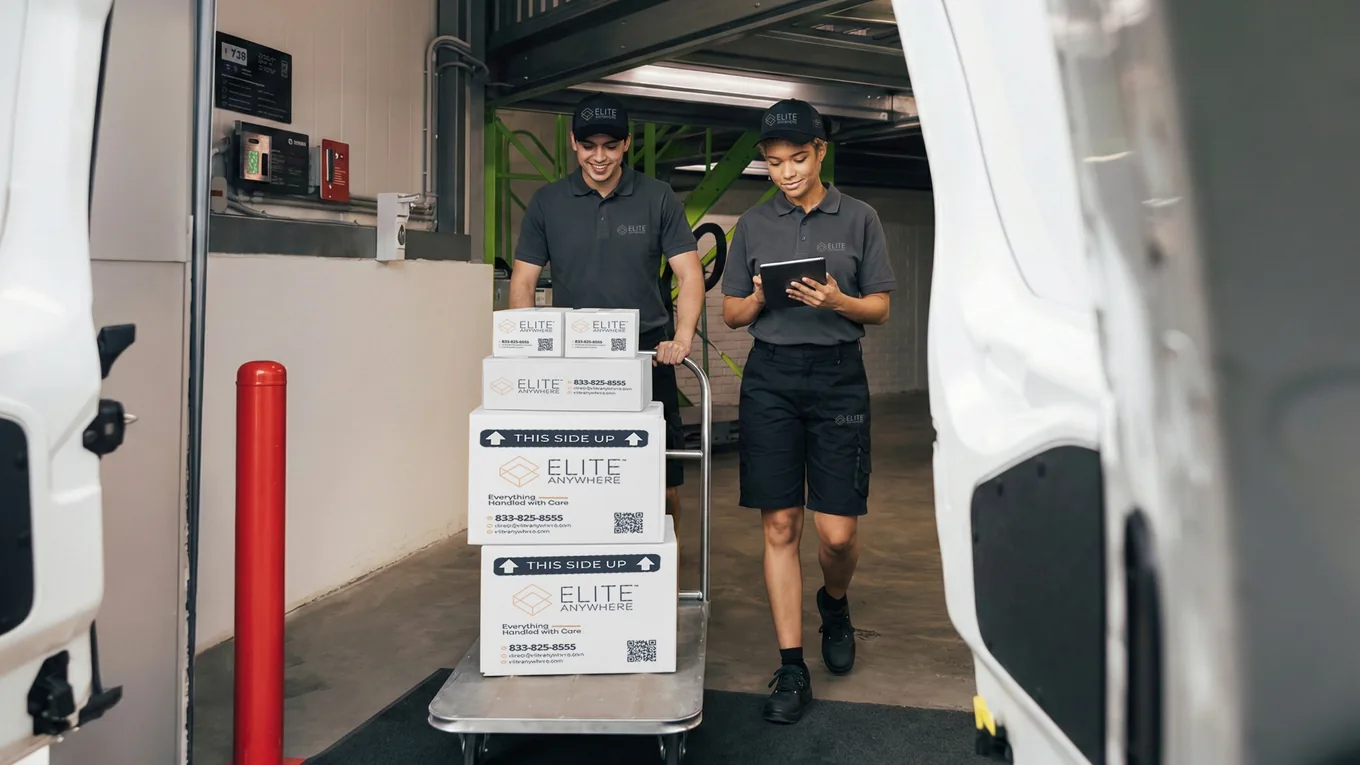 Elite Anywhere warehouse loading dock — branded boxes on a hand cart after customs clearance