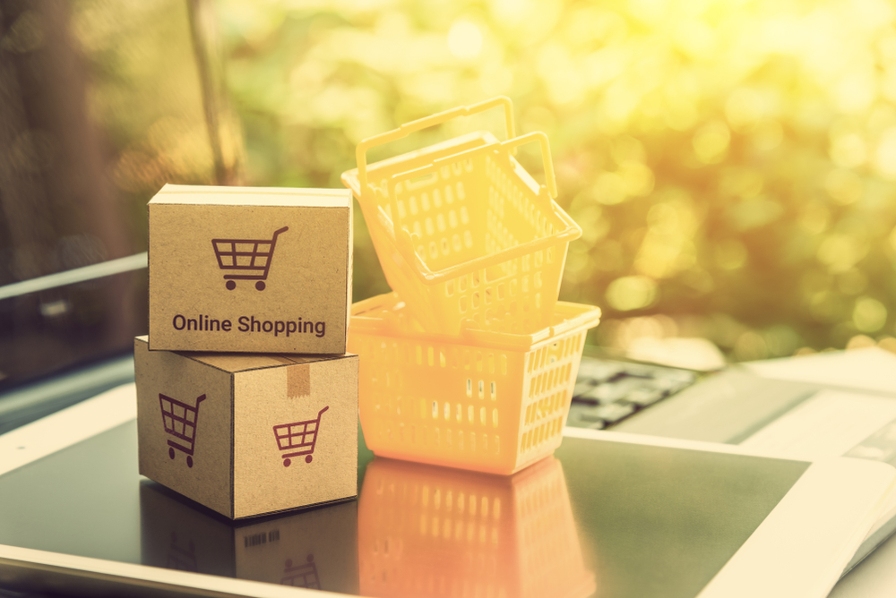 Online shopping / retail ecommerce and delivery service concept : Boxes with a shopping cart sign on a tablet and laptop, depicts consumers purchase or order products from suppliers or digital stores.